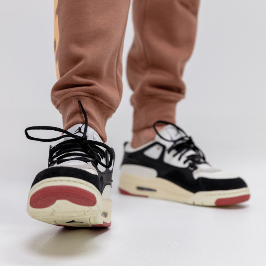 Pantofi Air Jordan 4 RM Canyon Rust purtați cu pantaloni maro deschis pe fundal alb