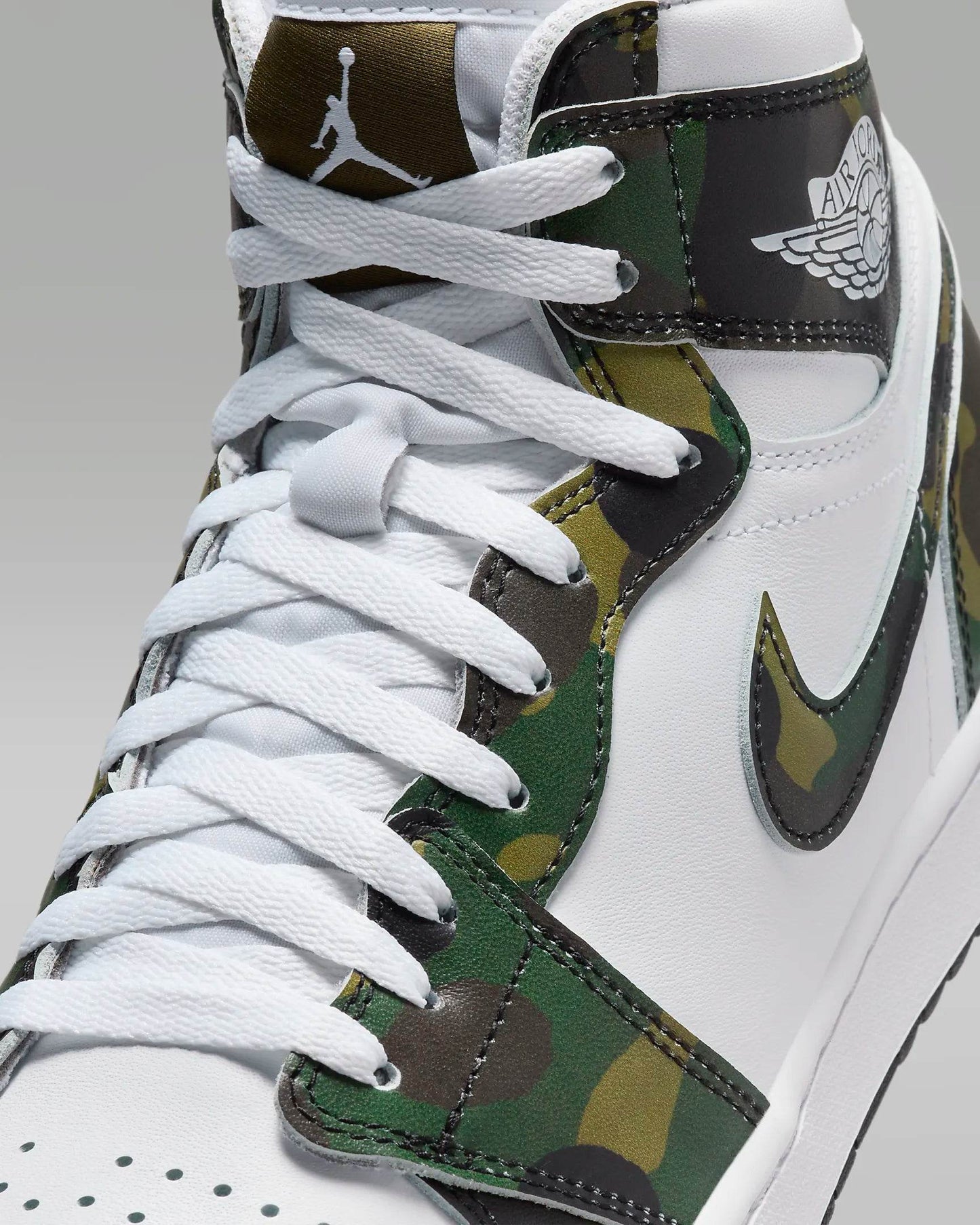 Detaliu în prim plan cu șireturile și designul camuflaj al pantofilor Air Jordan 1 High Golf Camo