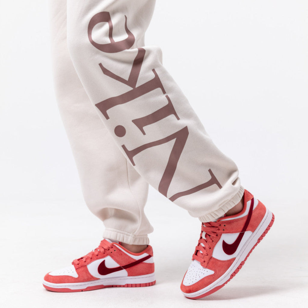 Adidași Nike Dunk Low Valentine's Day în nuanțe de roz și alb, purtați cu pantaloni casual bej