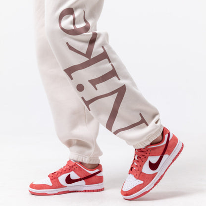 Adidași Nike Dunk Low Valentine's Day în nuanțe de roz și alb, purtați cu pantaloni casual bej